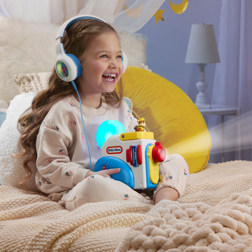 Child wearing headphones holding a 
Story Dream Machine in a cozy room