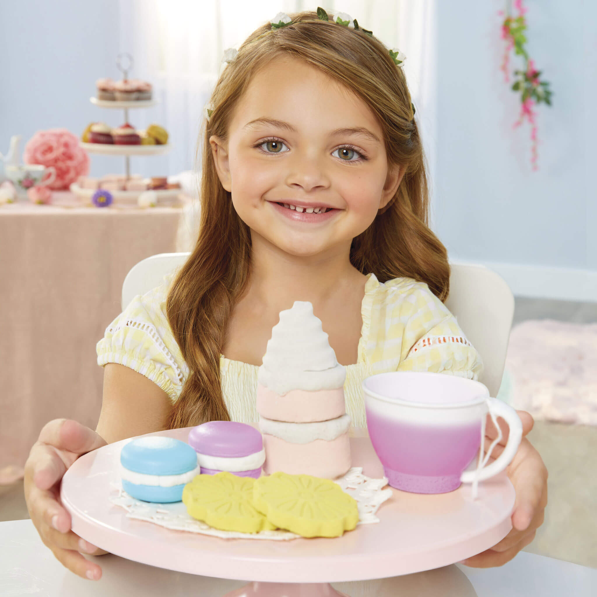 Young girl holding a tray with toy food and a cup 