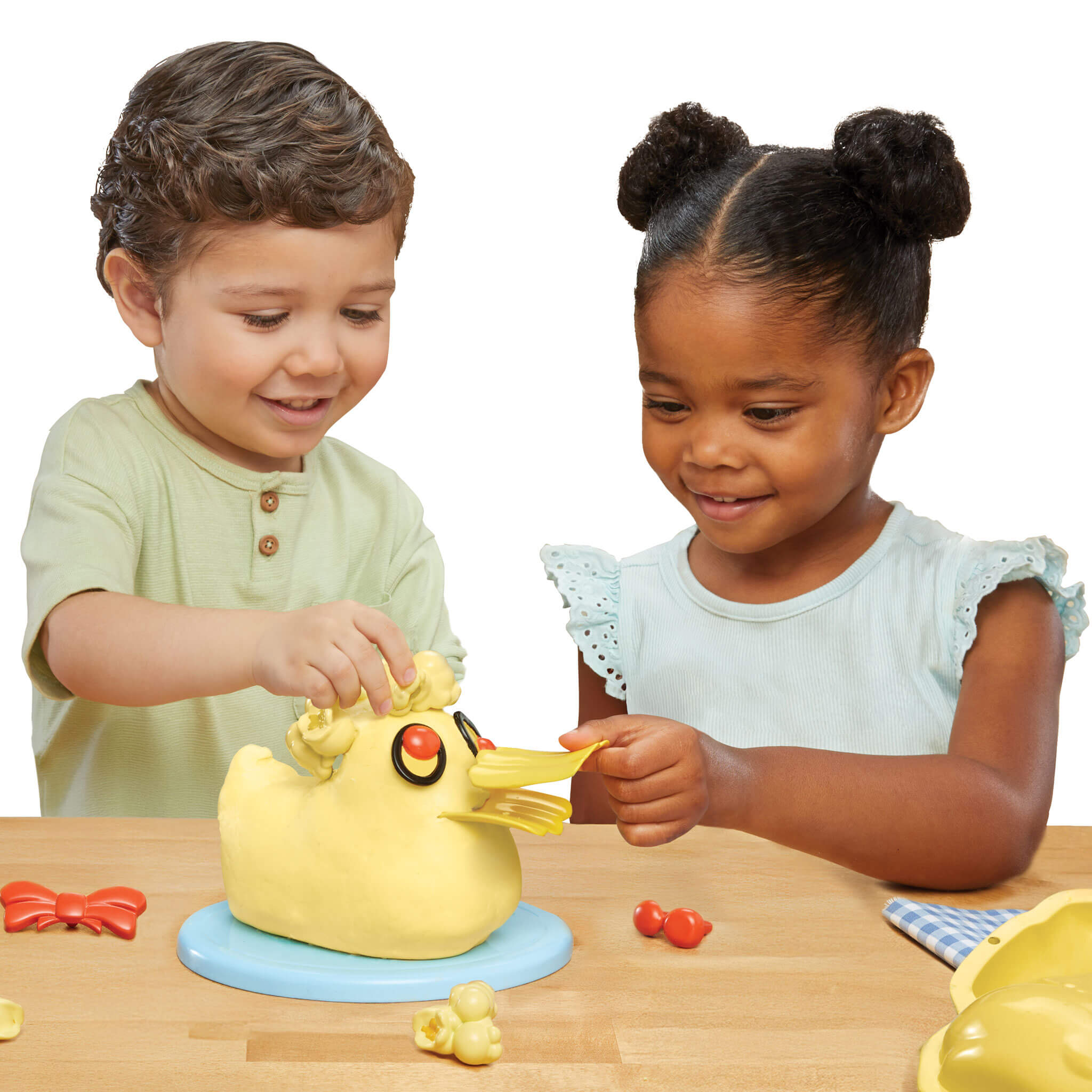 Two children making the yellow duck on a wooden table.